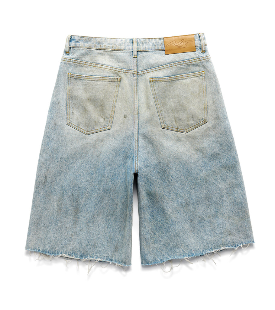 Flat lay photography of light-wash denim shorts, back view showing patch pockets and raw hem