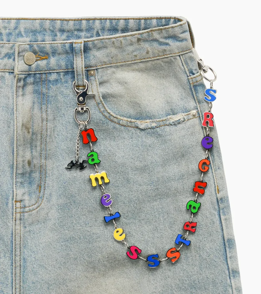 Detail flat lay photography of denim shorts with a colorful letter-charm chain accessory