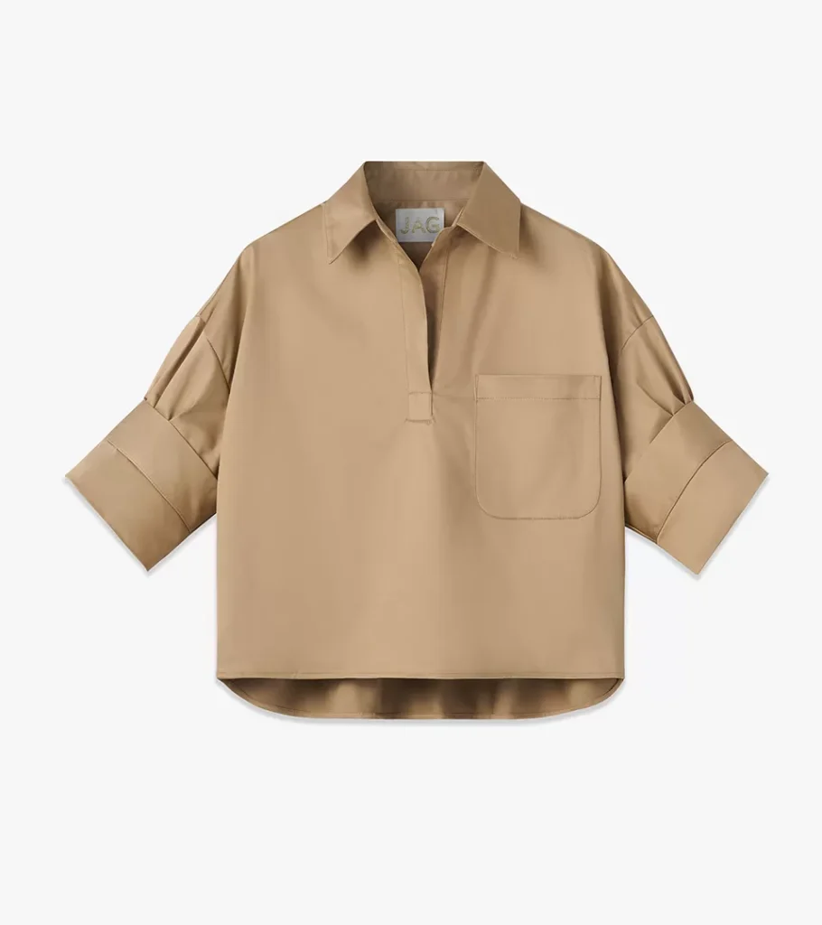 Flat lay photography of a tan popover shirt with chest pocket and cuffed sleeves