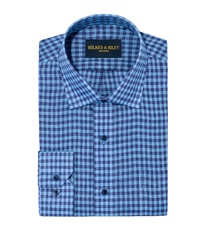 White background product photography of a blue check dress shirt folded with collar and cuff displayed