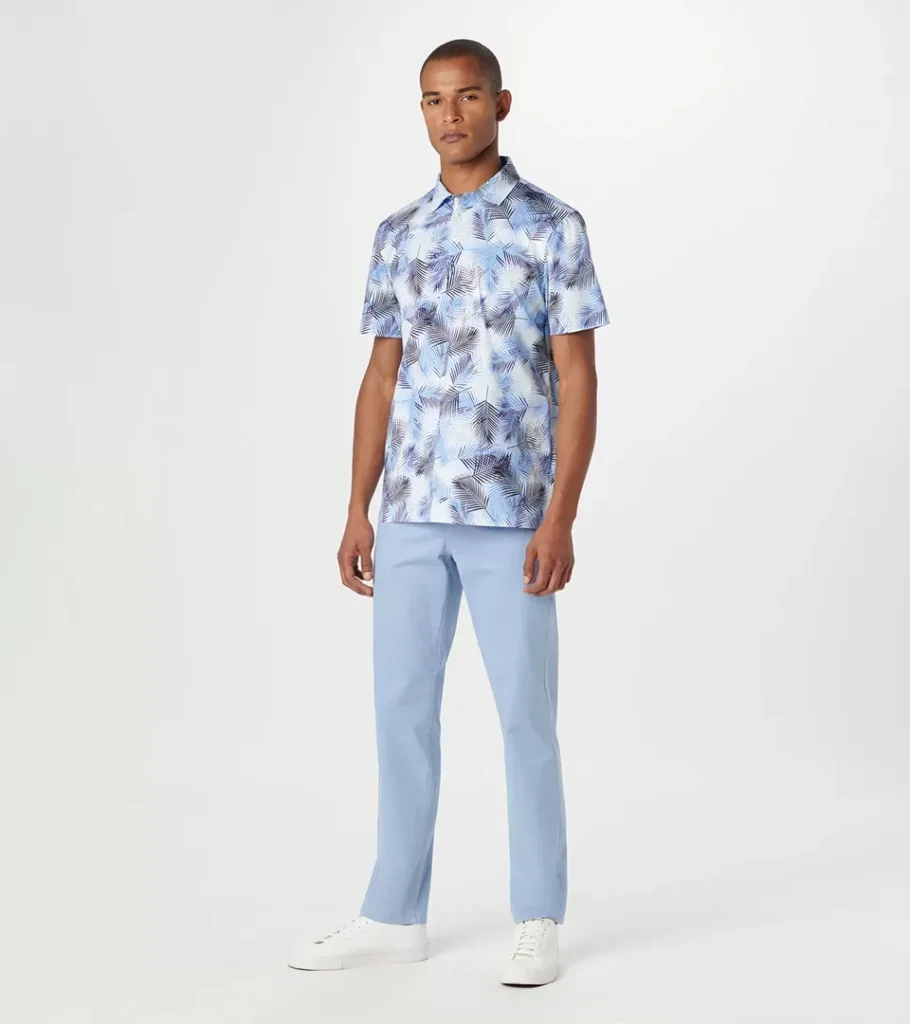On-model photography of a palm print short-sleeve shirt with light blue trousers and white sneakers
