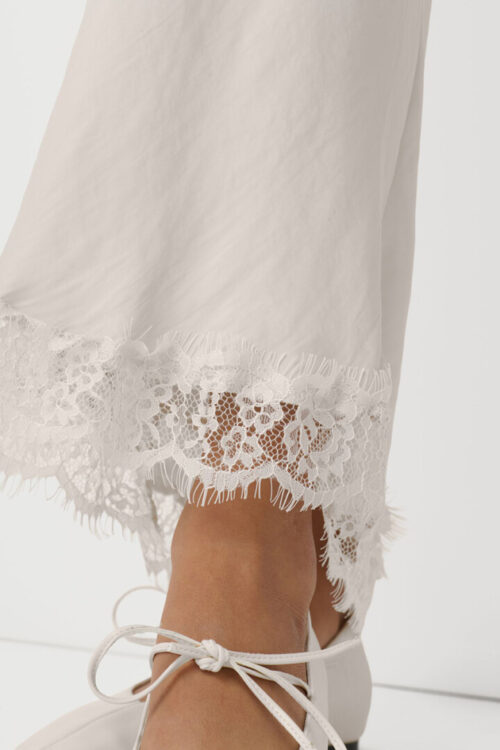 On-model photography of a cream knit sweater in side profile showing the drop-shoulder seam and sleeve