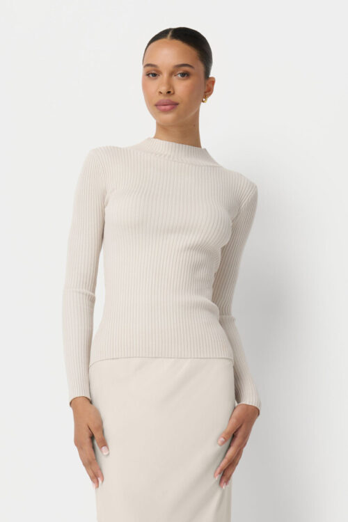 On-model photography of a cream ribbed knit top paired with a matching fitted skirt