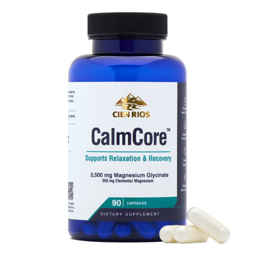 Product photography of a blue magnesium supplement bottle with white capsules beside it, hero shot on white