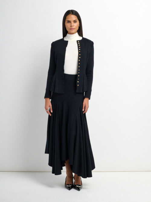 On-model photography of a black stud-trimmed collarless jacket and flared asymmetric midi skirt with a white turtleneck