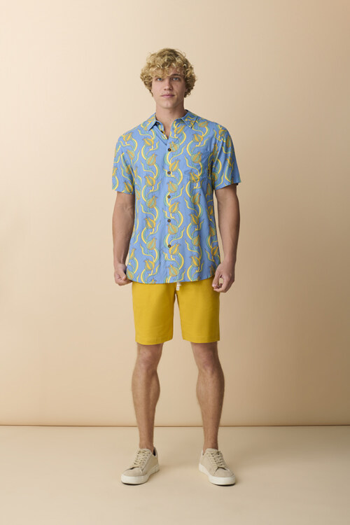 Male model wearing blue tropical print shirt and yellow shorts