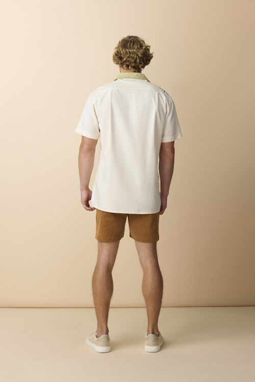 Male model wearing tropical print shirt and green shorts in studio