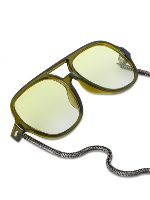 Close-up product photography of olive aviator sunglasses with yellow-green lenses and a woven metal chain