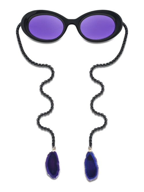 Product photography of black oval sunglasses with purple lenses and a black chain with blue agate pendants
