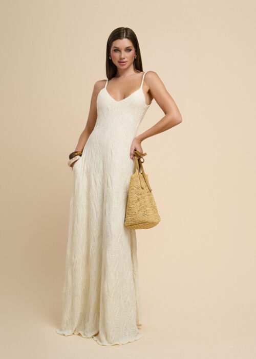 On-model photography of a textured cream slip maxi dress styled with a woven raffia handbag