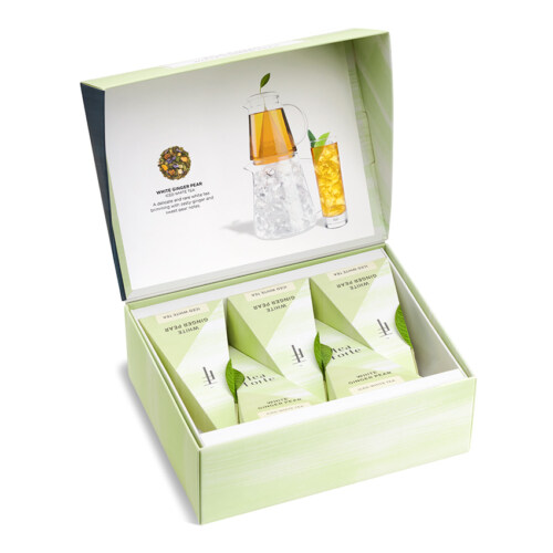 Product photography of an open green tea sampler box with pyramid infusers and brewing illustration inside the lid