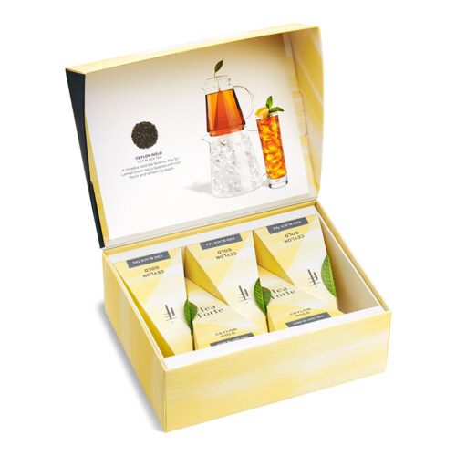 Product photography of an open yellow tea sampler gift box with black tea infusers and iced tea imagery on the lid