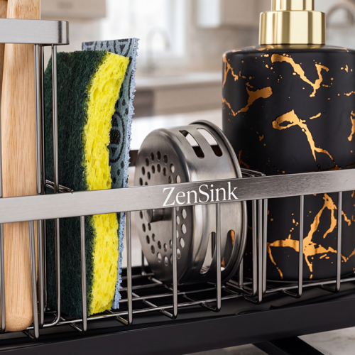 Close-up product photography of a sink caddy rail with sponge, drain stopper, and marbled soap dispenser