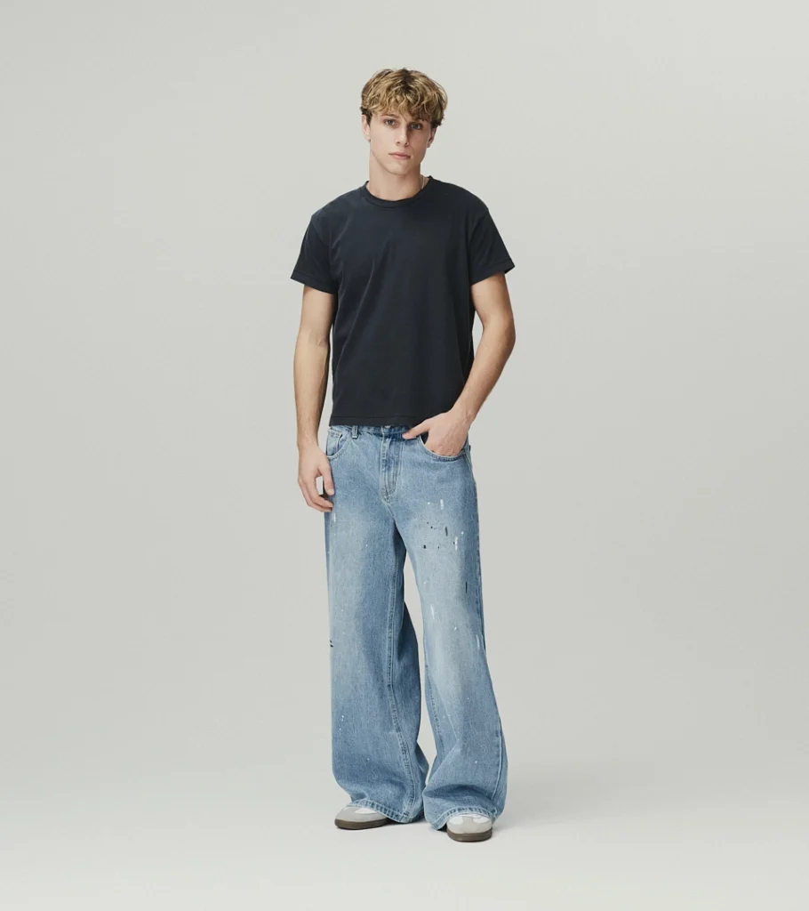 On-model photography of a dark grey t-shirt and baggy light wash jeans, front view