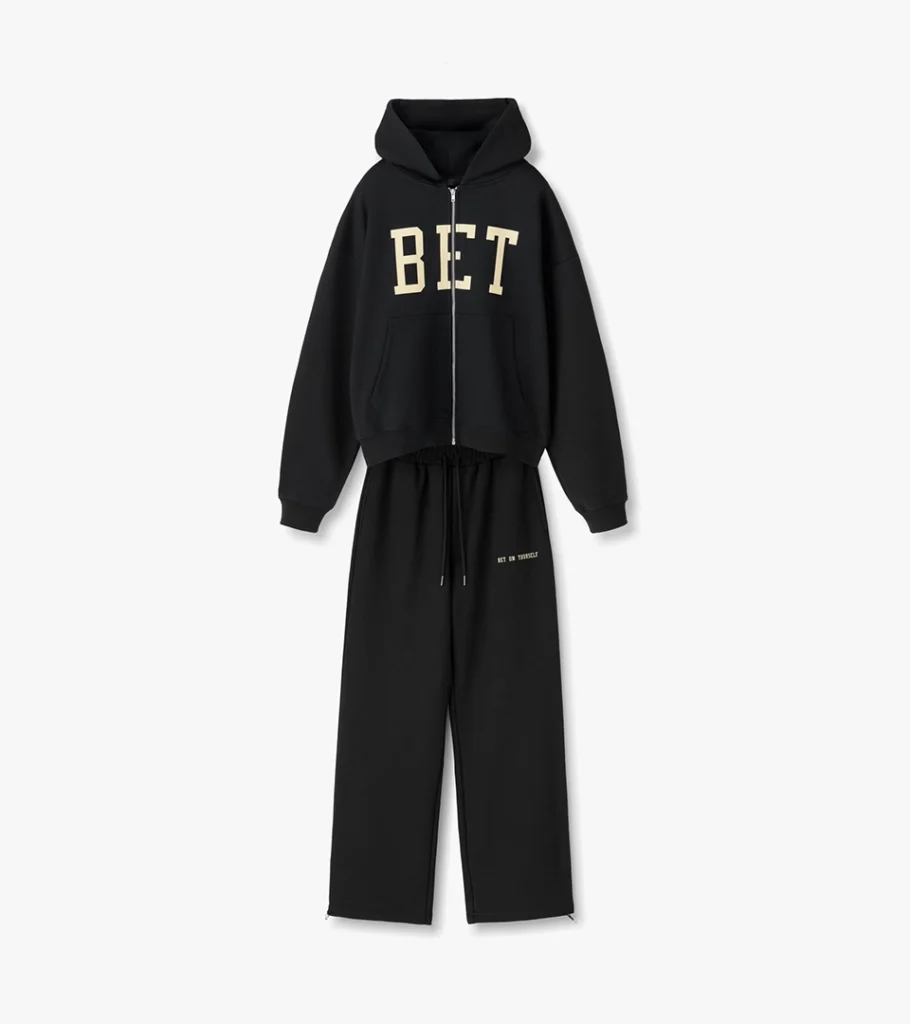 Flat lay photography of a black hoodie and sweatpants set with varsity lettering