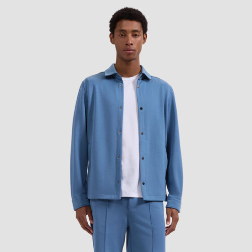 Model wearing blue overshirt over white tee with blue shorts, front view