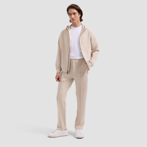 Full-length front view of model wearing cream fleece hoodie and jogger set with white sneakers