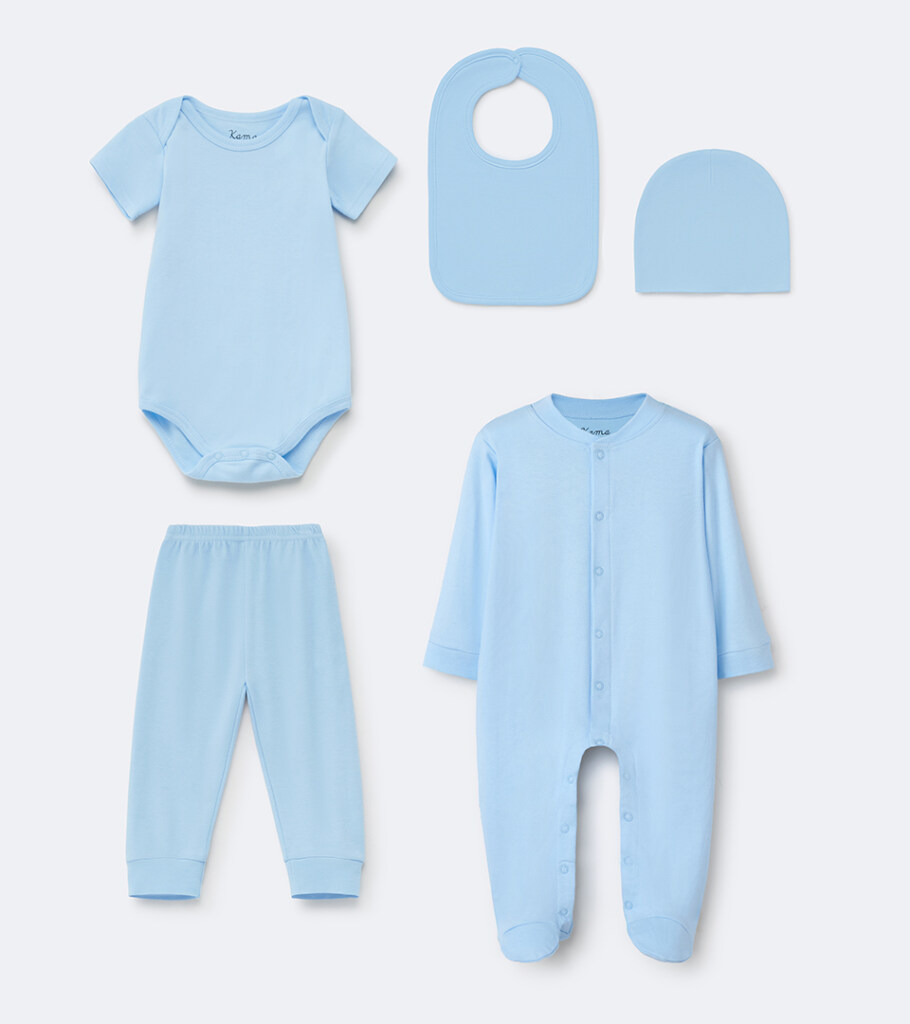 Group flat lay photography of a light blue baby layette set with bodysuit, bib, hat, pants, and sleeper