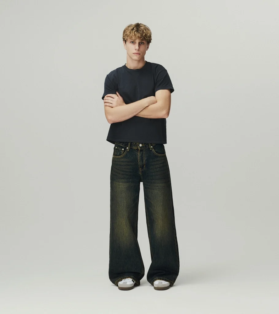 On-model photography of a dark t-shirt and vintage wash wide-leg jeans, arms crossed