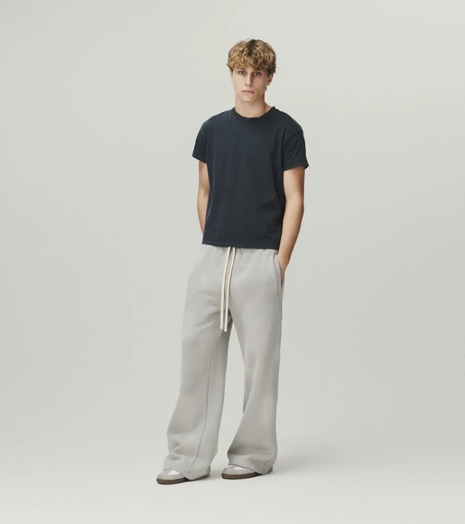 On-model photography of a dark t-shirt with light grey drawstring sweatpants, relaxed pose