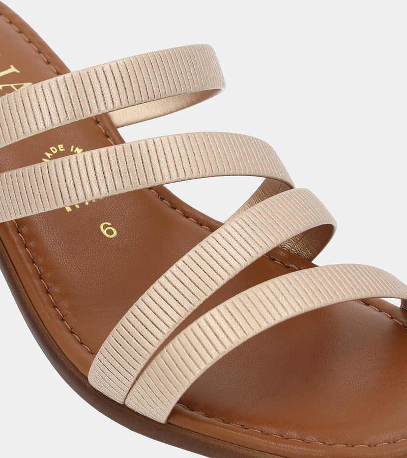 Close-up automated product photography of the cream webbing straps and stitching on a tan leather slide sandal