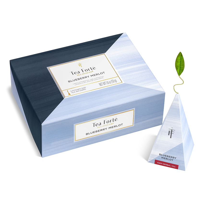 Product photography of a closed pale blue tea carton with a single pyramid sachet standing beside it