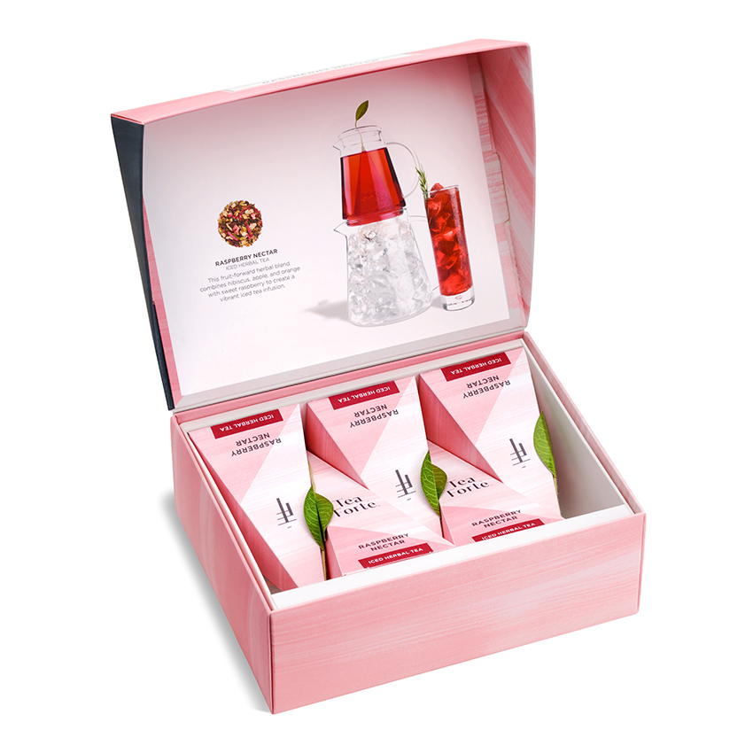 Product photography of an open pink gift box of pyramid tea sachets with a printed insert showing an iced tea serve