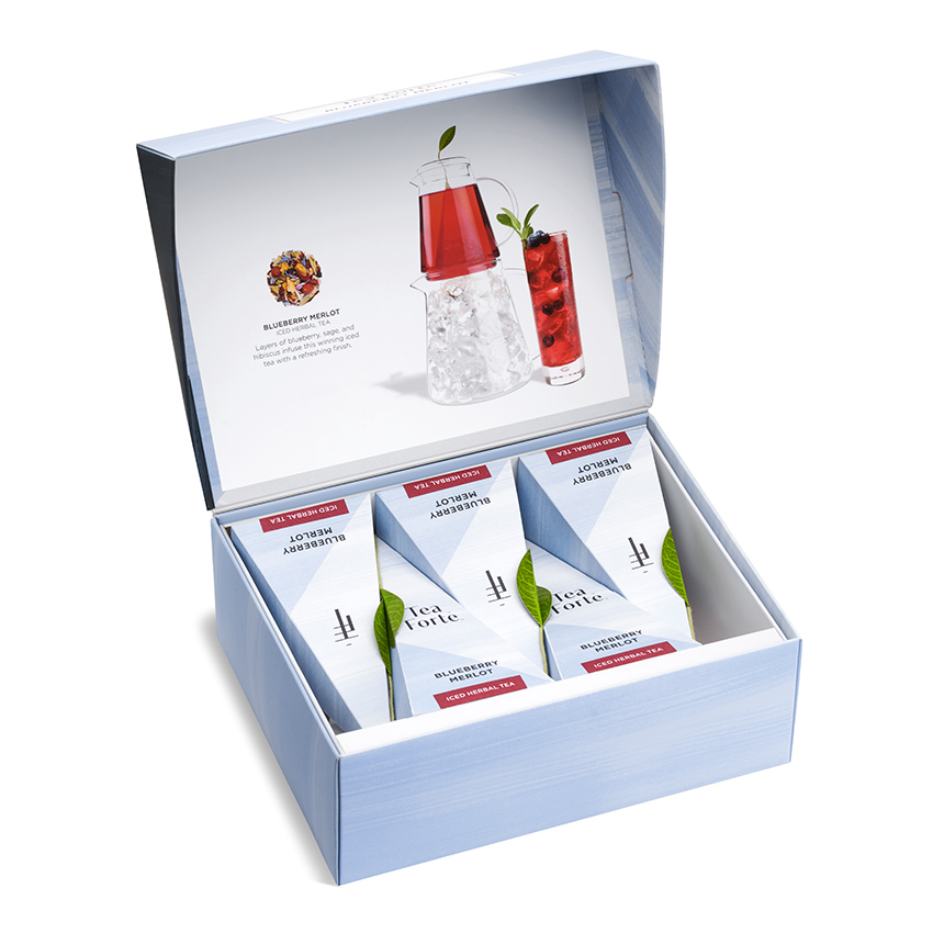 Product photography of an open pale blue gift box of pyramid tea sachets with a printed insert showing a red iced tea serve