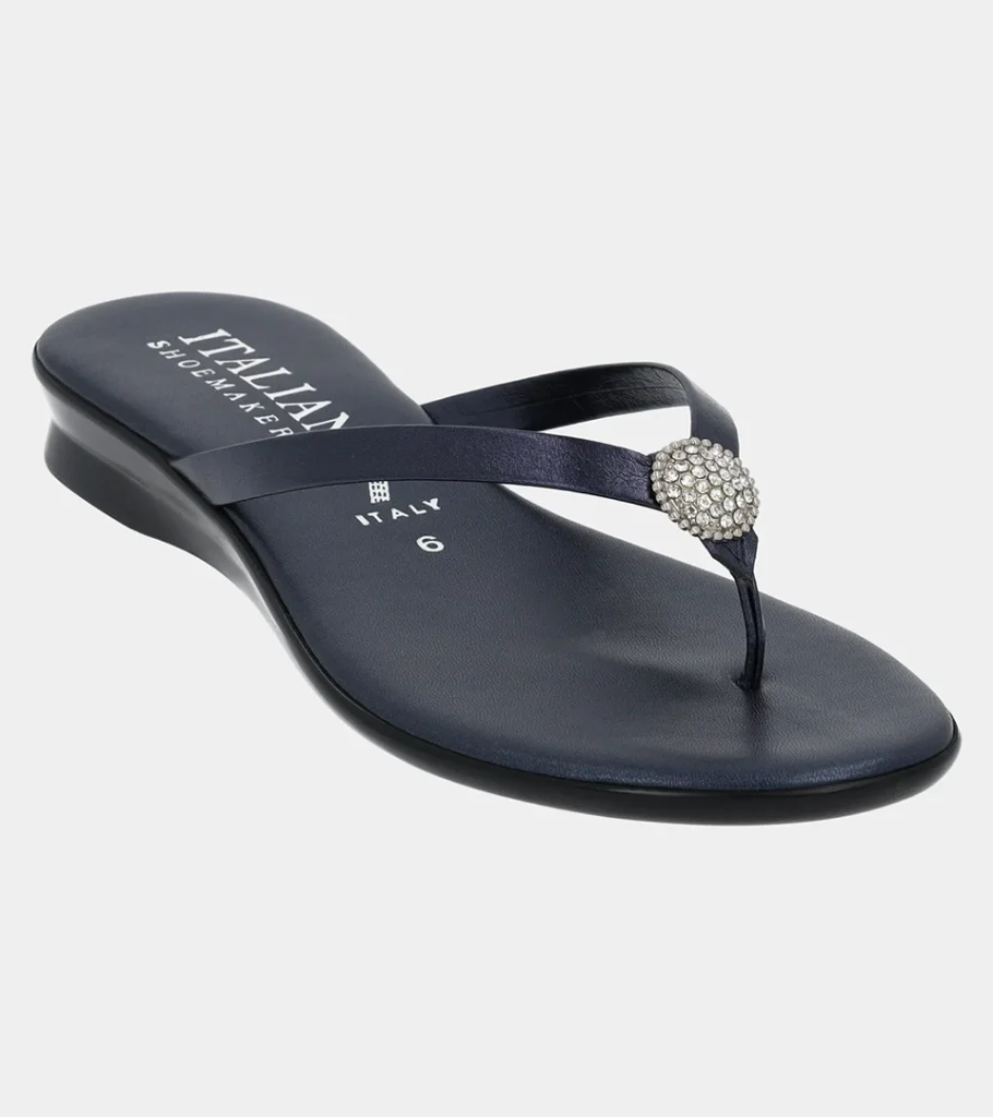 Automated product photography of a black thong sandal with a round crystal ornament on a low wedge sole, side view