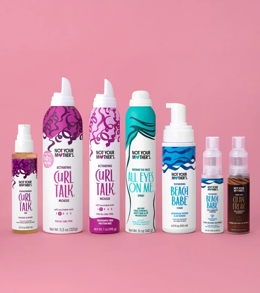 Grouped product photography of nine haircare bottles and cans of varying heights arranged as a set on a pink background