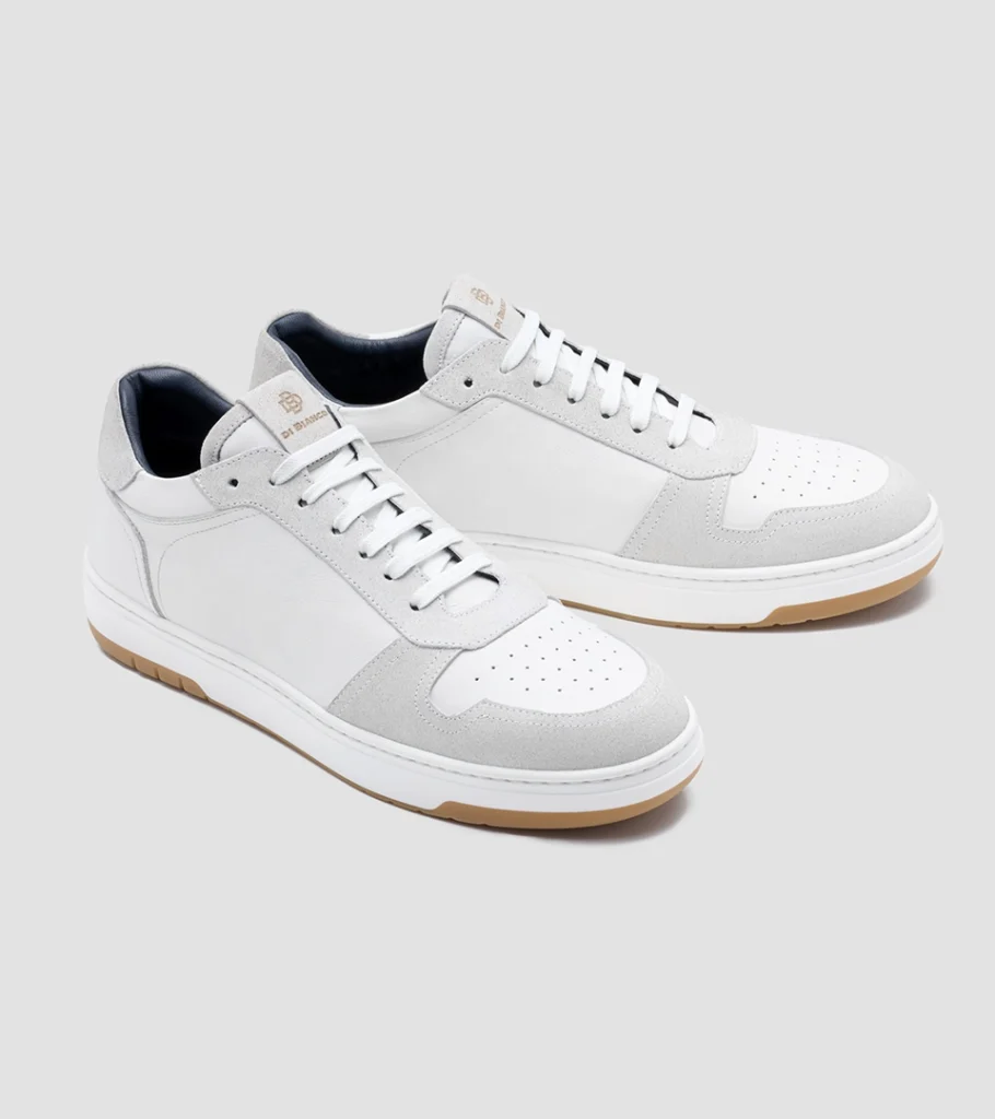 Shoe product photography of a white leather sneaker at a front three-quarter angle with a gum outsole