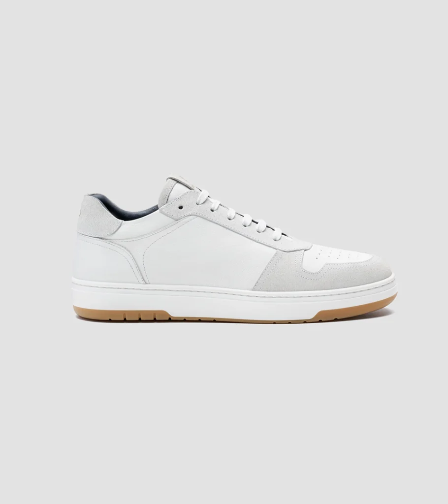 Shoe product photography of a white leather sneaker in side profile showing the gum outsole and side panel