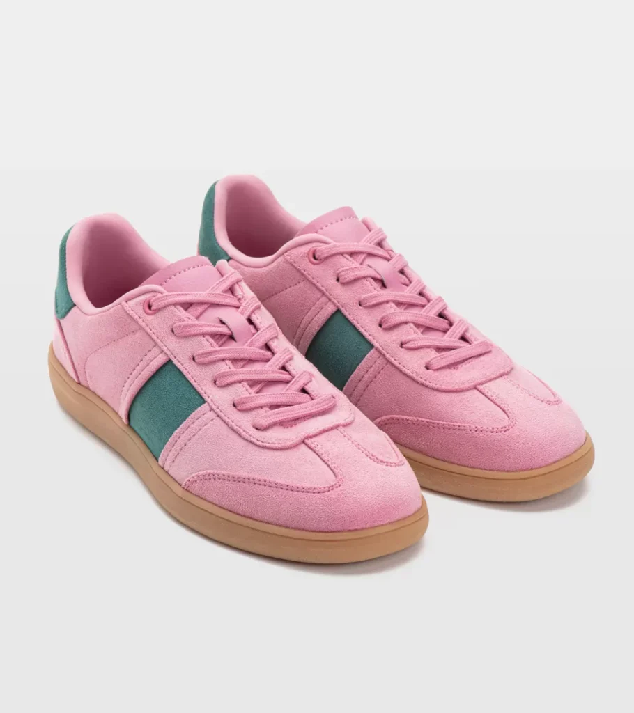 Shoe product photography of a pair of pink retro trainers at a raised three-quarter angle with green stripe detail