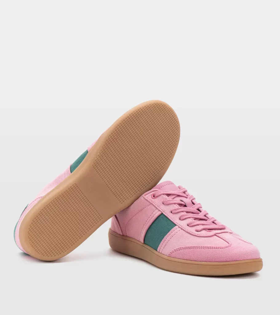 Shoe product photography of a pair of pink retro trainers with one shoe tipped to reveal the gum outsole