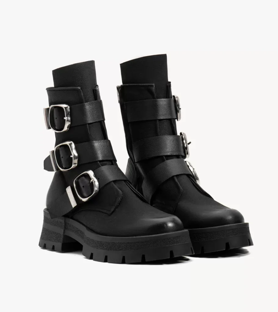 Shoe product photography of a pair of black buckled combat boots at a front three-quarter angle