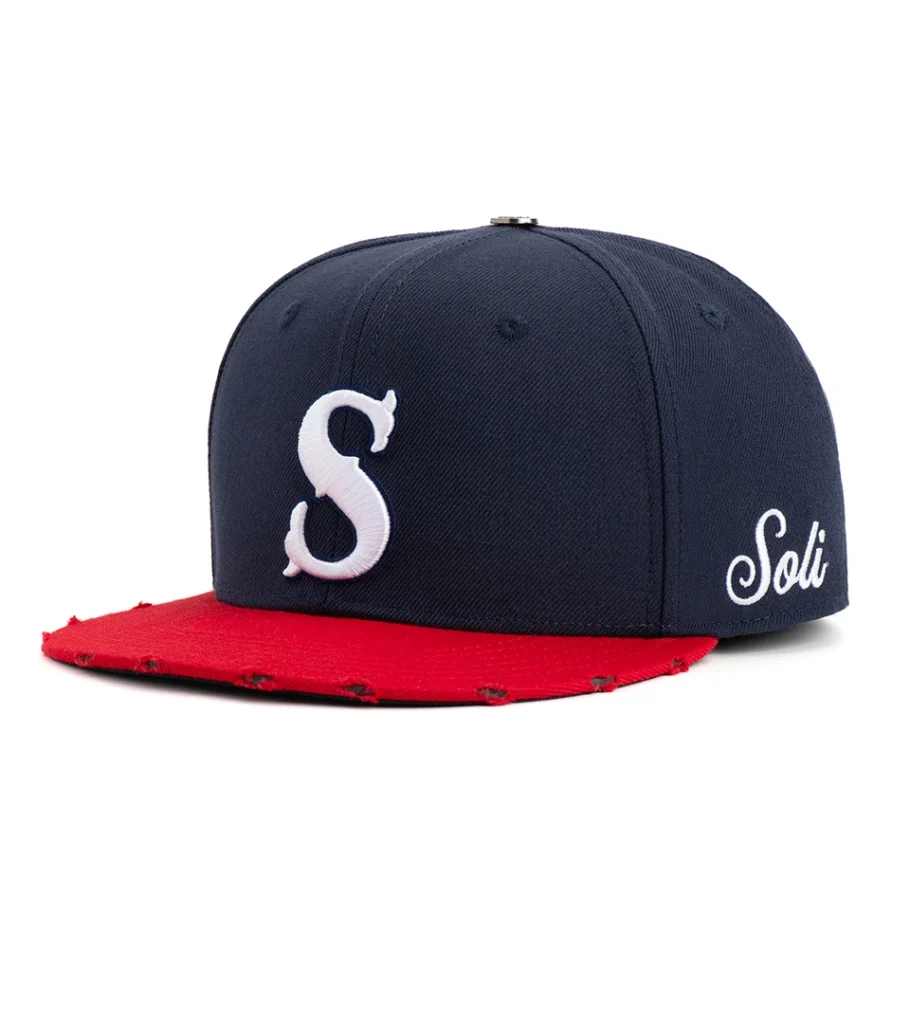 Product photography of a navy snapback cap with a distressed red brim and white embroidered lettering