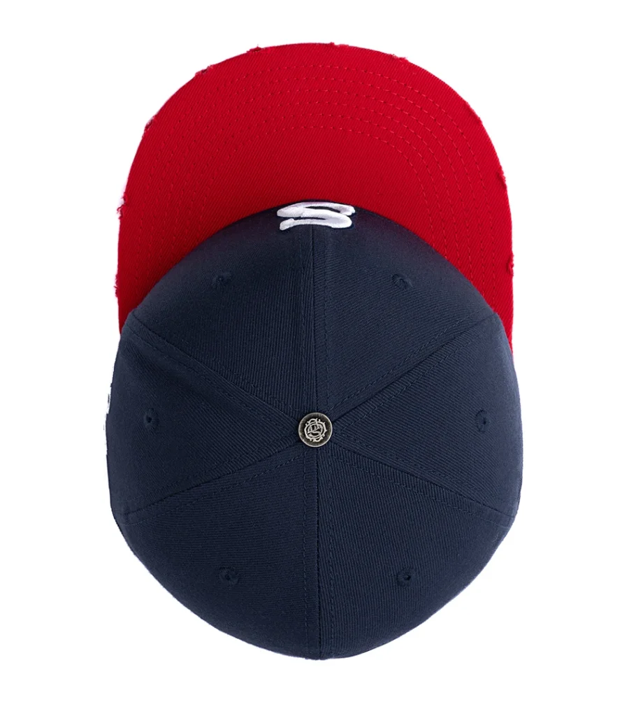 Product photography of a navy baseball cap shown from above, revealing the red underbrim