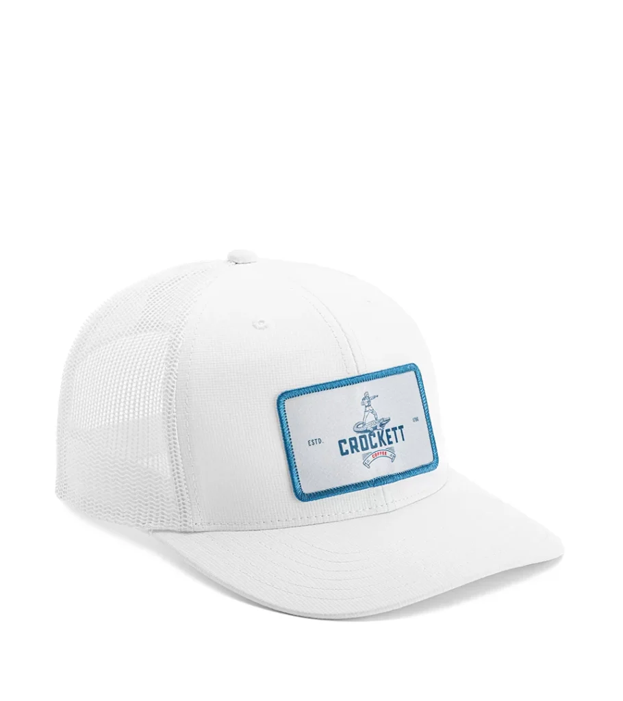 Product photography of a white trucker cap with a rectangular woven patch, angled view