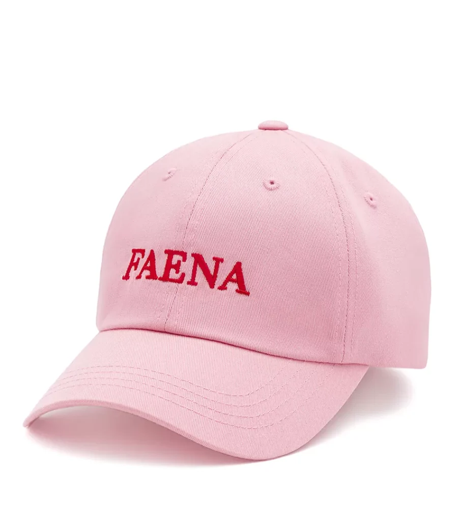 Product photography of a pink cotton cap with red embroidered lettering, front angled view