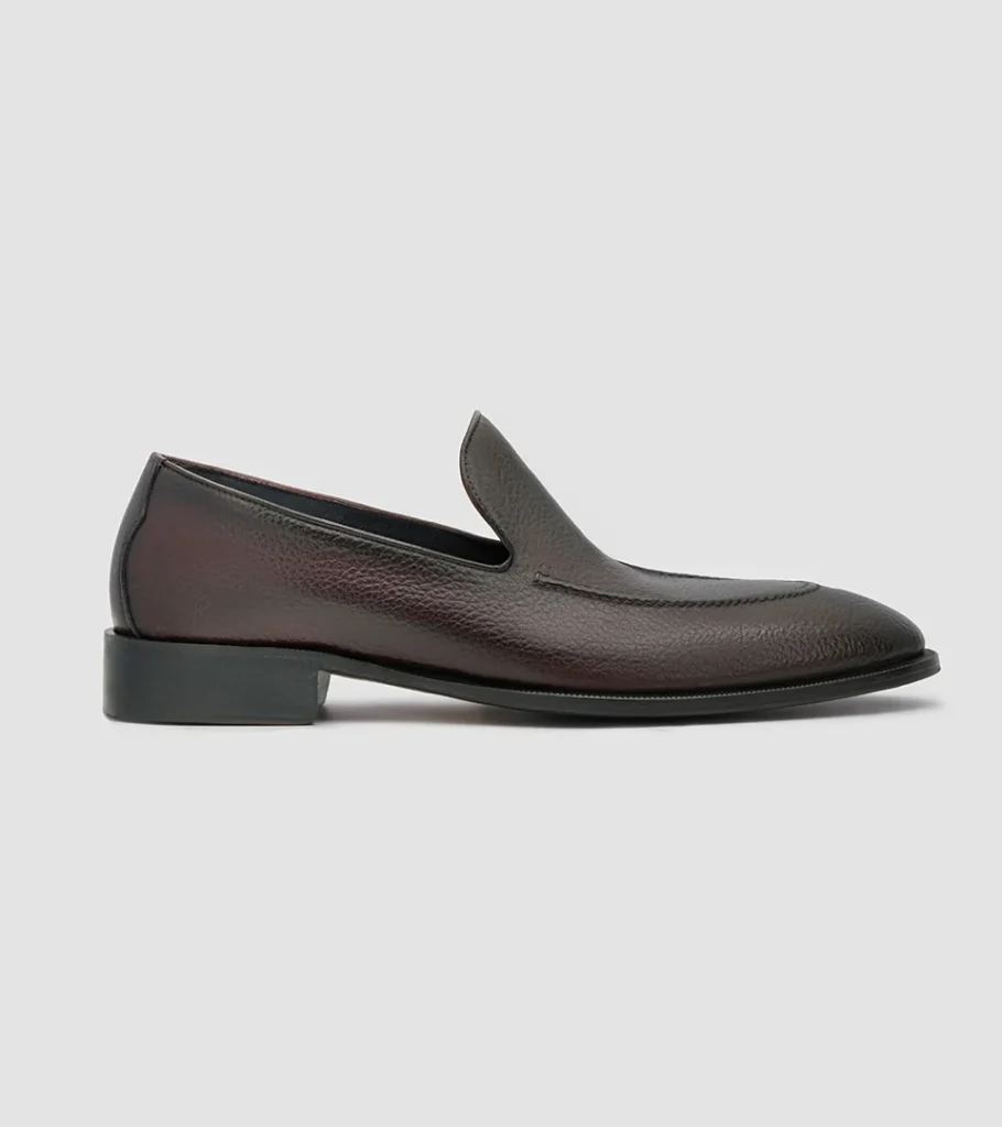 Shoe product photography of a dark espresso leather loafer in side profile on a soft grey background