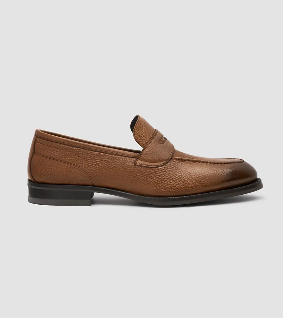 Shoe product photography of a light cognac leather penny loafer in side profile with a stacked heel