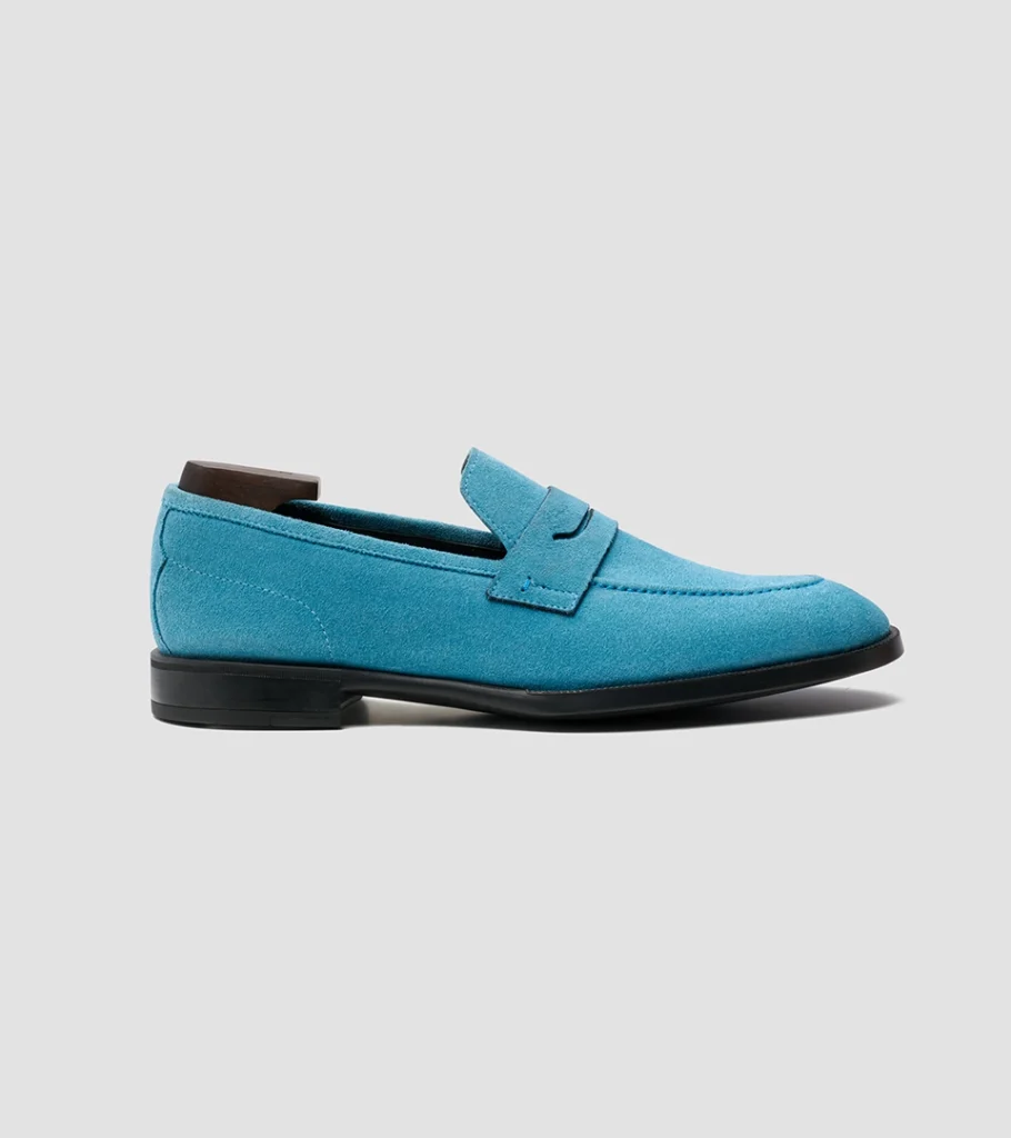 Shoe product photography of a turquoise suede penny loafer in side profile with a dark leather sole