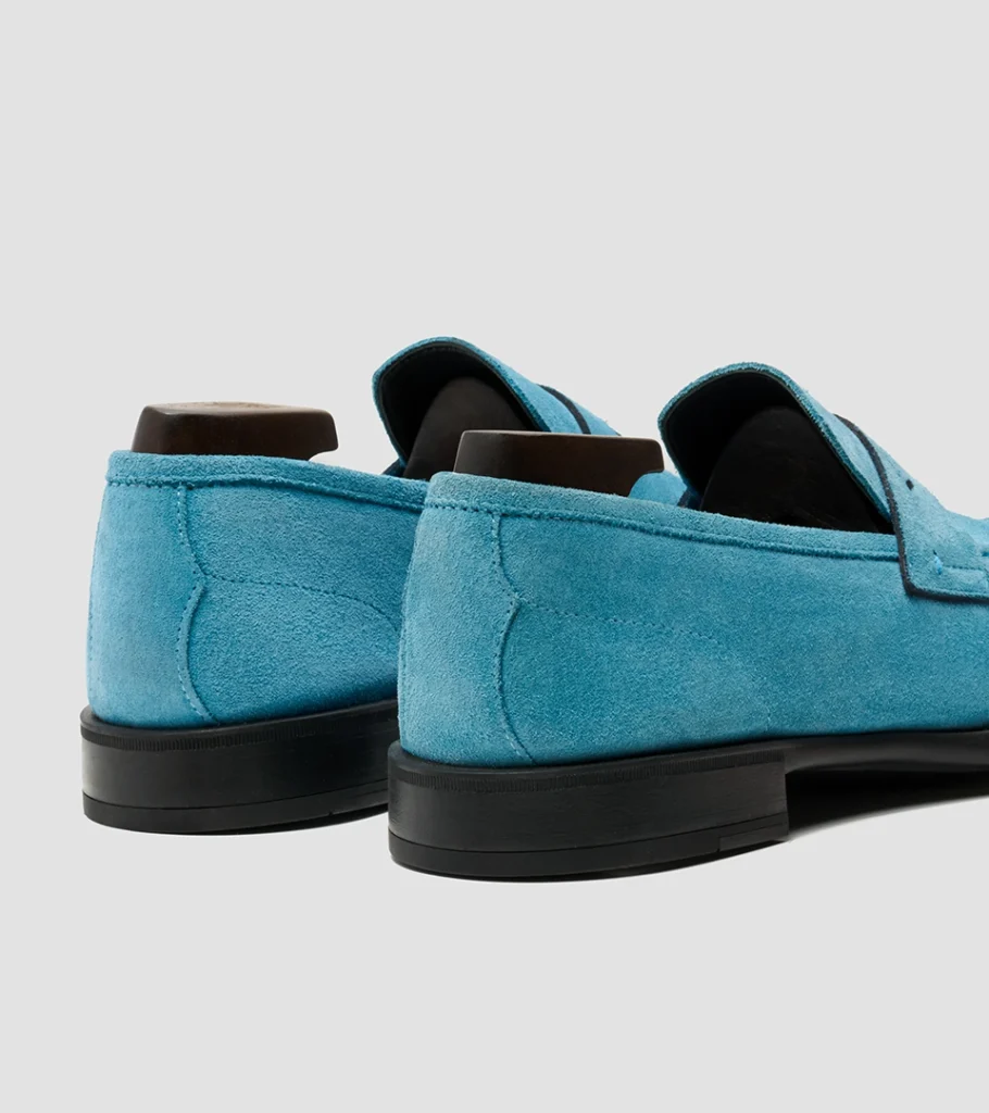 Shoe product photography of a pair of turquoise suede loafers viewed from behind at a three-quarter angle
