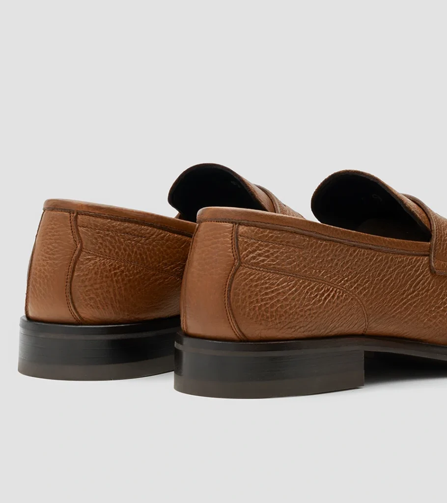 Shoe product photography of a pair of tan grained leather loafers viewed from behind at a three-quarter angle