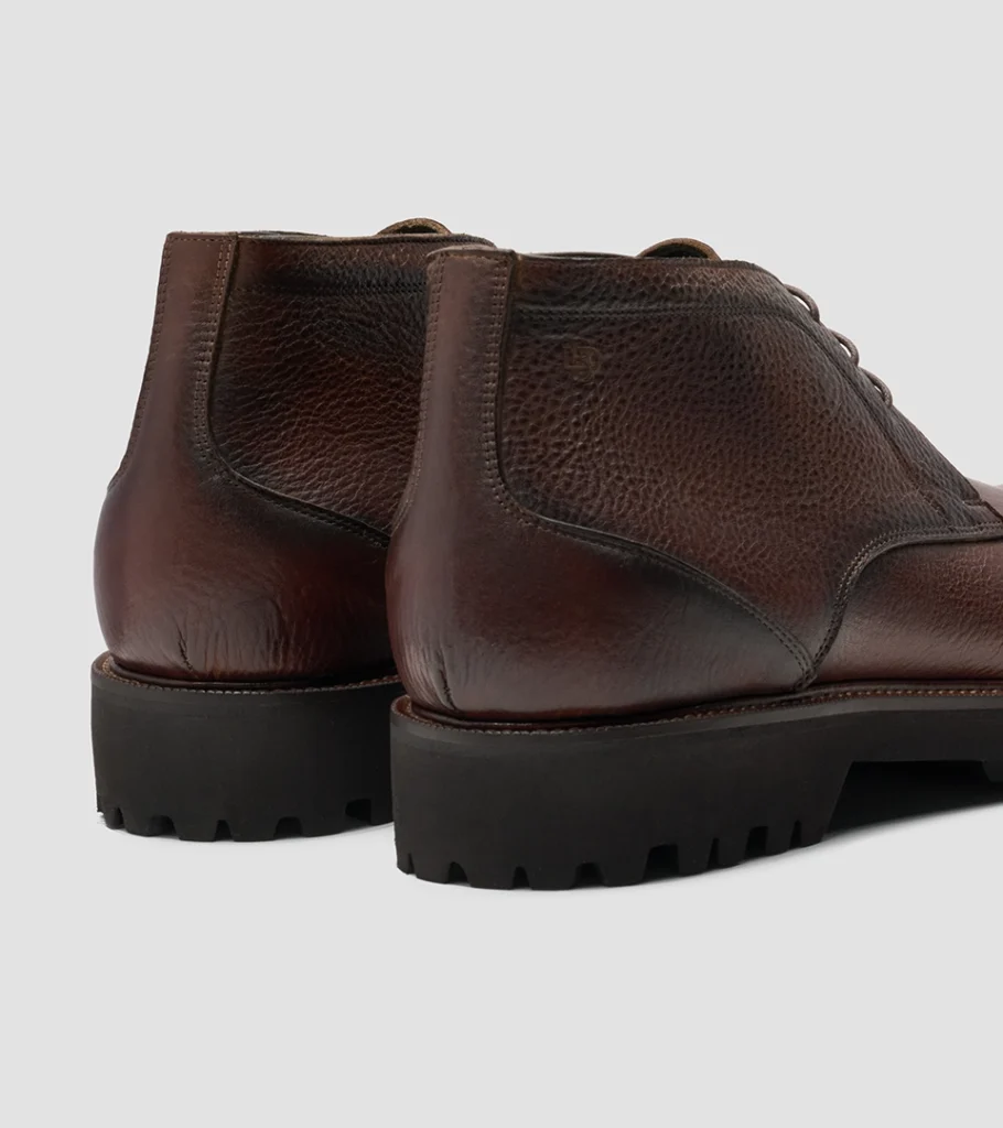 Shoe product photography of a pair of burgundy leather boots viewed from behind showing heel and welt detail
