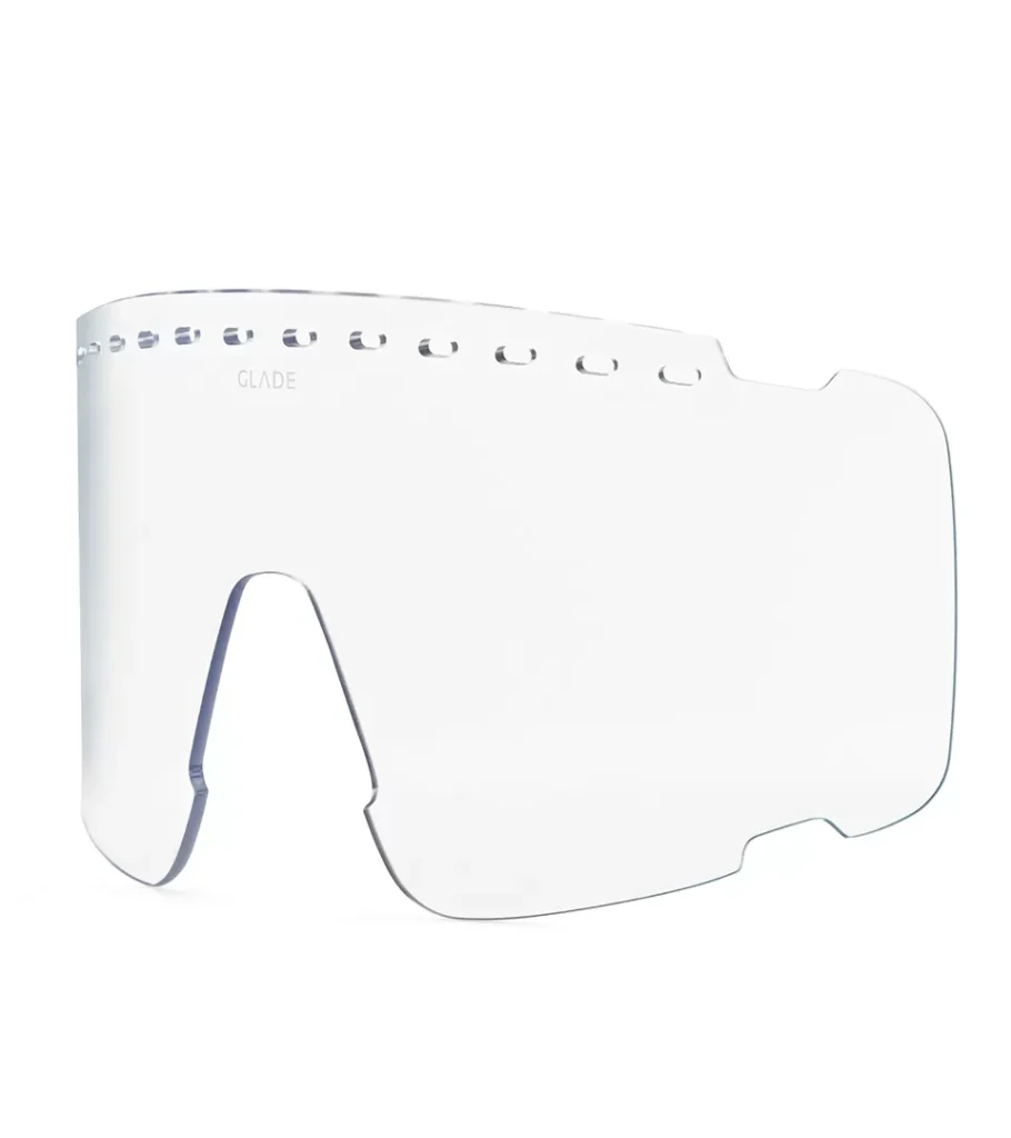 Product photography of a clear replacement goggle lens with vent perforations, angled view