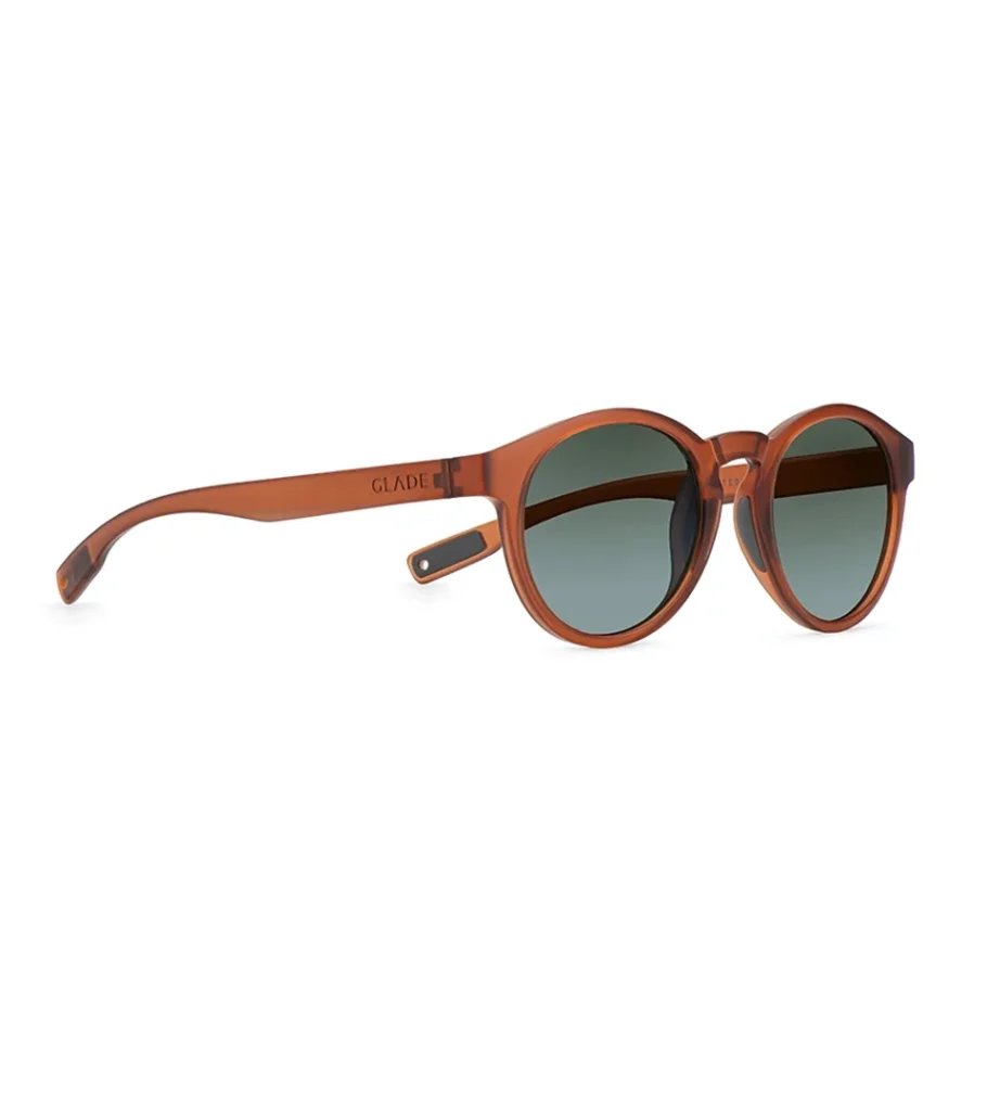Product photography of round amber sunglasses at a three-quarter angle showing the temple arm