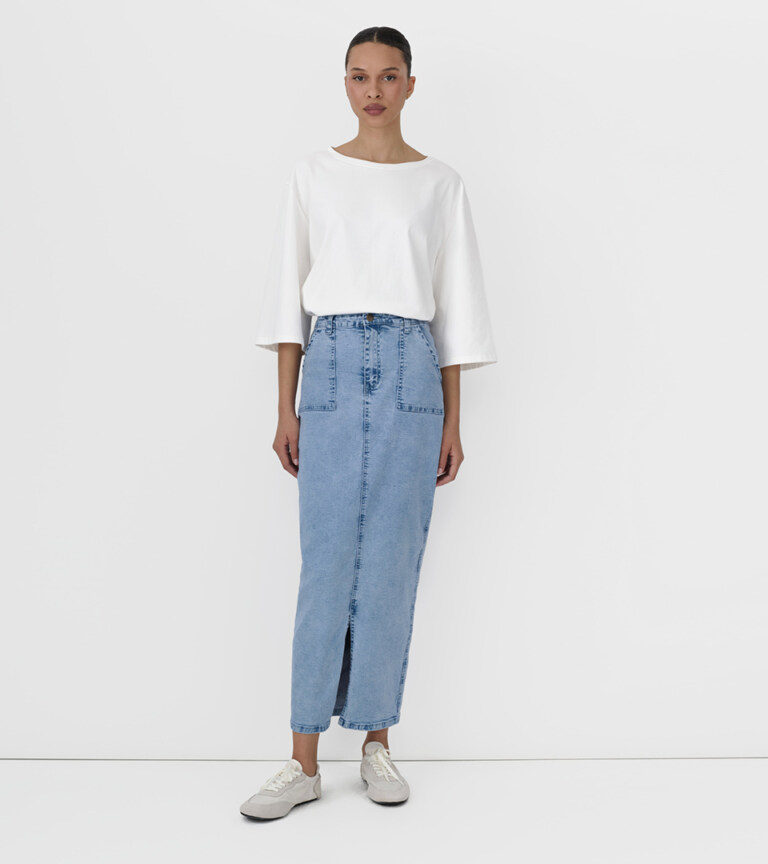 open suitcase flat lay styled with white ribbed top ballet flats and accessories on white background