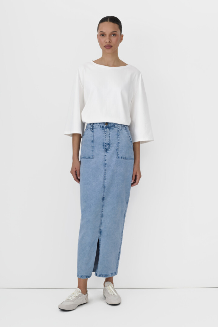 All-in-one content production for clothing brands by Shootify. Model in white oversized tee and light blue denim midi skirt on white.