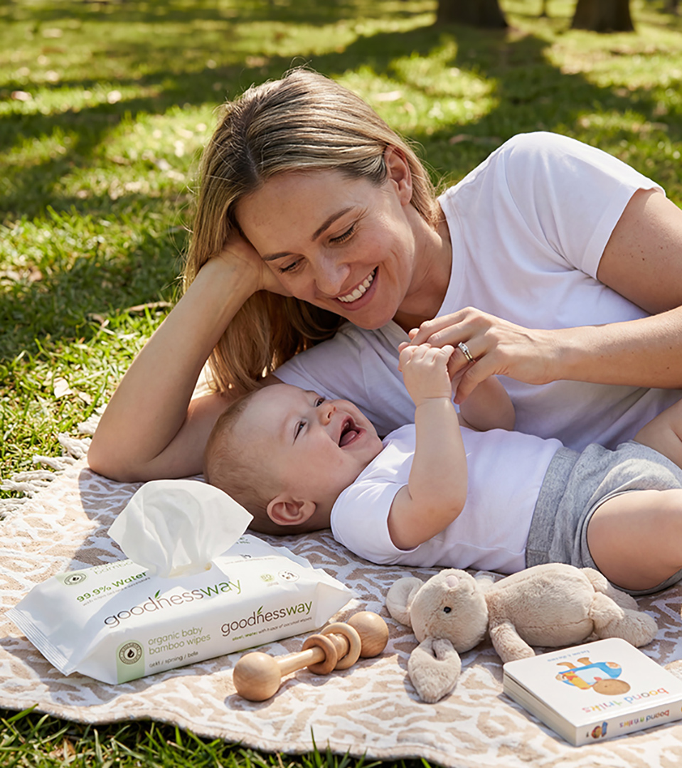 mother and baby playing on picnic blanket outdoors next to baby wipes product for lifestyle photography